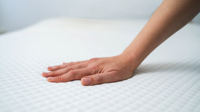 mano tocando un colchon blanco